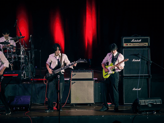 Russell playing electric guitar with his school band under moving stage lights